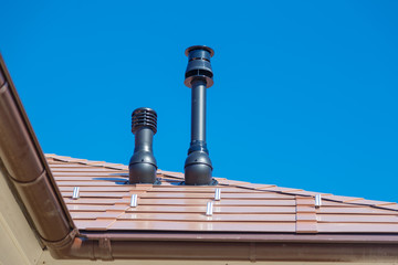 Naklejka premium Exhaust pipe on the private house roof