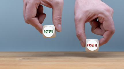 Being active or passive? Two Hands hold two dice with the words 