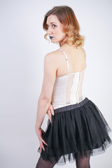 Naklejka premium charming caucasian blonde in lace beige lingerie bodice and black skirt on white background in Studio