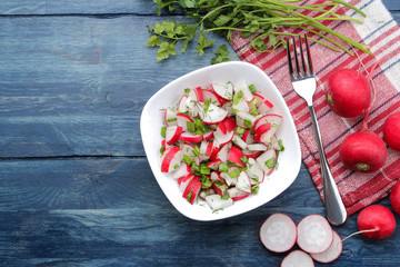 Salad of fresh radishes and fresh herbs on a blue wooden table. Spring vegetable salad. ingredients for cooking salad. top view