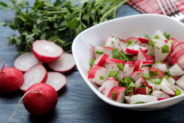Salad of fresh radishes and fresh herbs on a blue wooden table. Spring vegetable salad. ingredients for cooking salad.