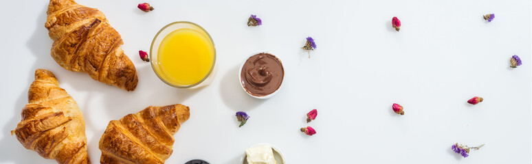 panoramic shot of tasty croissants near bowl with chocolate cream, orange juice and dried flowers on white
