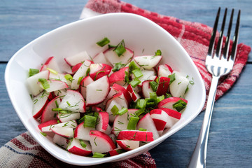 Salad of fresh radishes and fresh herbs on a blue wooden table. Spring vegetable salad.