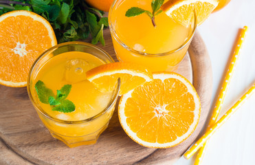 Close-up of a glass of orange juice with oranges fruits on wooden and stone background. Vitamins and minerals. Healthy drink and beverage concept.