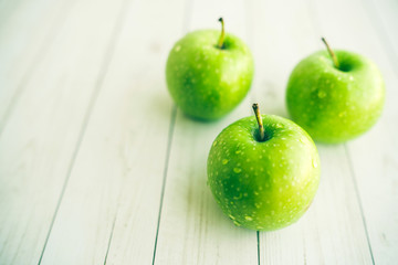 Juicy green apples on white background. Three apples with water drops on white wooden background
