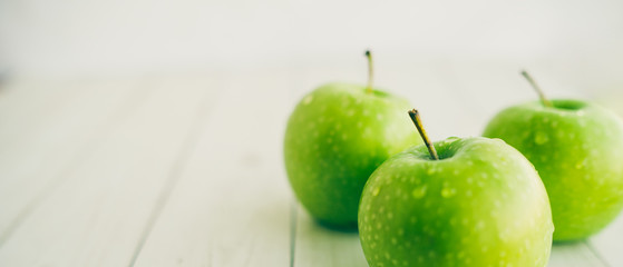 Juicy green apples on white background. Three apples with water drops on white wooden background	