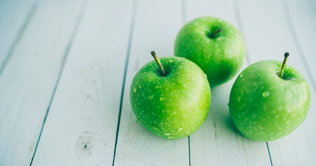 Juicy green apples on white background. Three apples with water drops on white wooden background