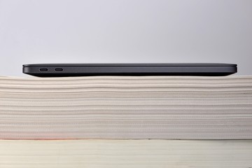 Laptop computer stacked upon thick soft cover book