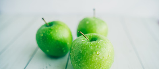 Juicy green apples on white background. Three apples with water drops on white wooden background