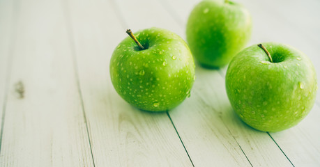 Juicy green apples on white background. Three apples with water drops on white wooden background