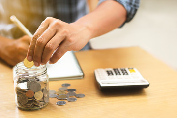 A businessman holding coins putting into the glass. concept saving money and finance accounting.