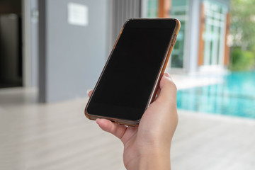 Female hand holding smartphone with blurred pool background, Business concept