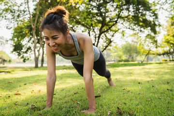 Naklejka na ściany i meble Healthy young Asian runner woman warm up her body by push up before exercise and yoga near lake at park under warm light morning. Lifestyle fitness and active women exercise in urban city concept.