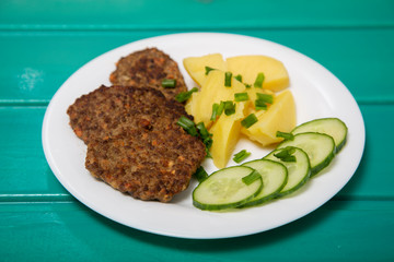 Fried liver pancakes or cutlets with potatoes and slices cucumber 