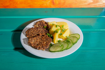 Fried liver pancakes or cutlets with potatoes and slices cucumber 