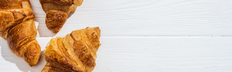 panoramic shot of tasty croissants on white surface