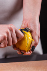 young woman in a gray aprons cuts lemon zest