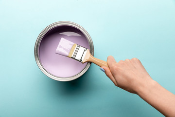 partial view of woman with brush and tin of purple paint on purple surface