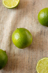 Whole and cut green citrus limes on cloth, top view. From above, overhead.