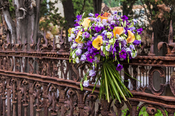 A bouquet of flowers on the wrought openwork fence on the Montjuic Cemetery closeup, Barcelona, Catalonia, Spain