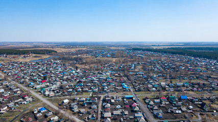 Aerial view of a large number of small houses with colored roofs on the outskirts of a small provincial town of Lenin Kuznetsk on an spring sunny day with the road and cars