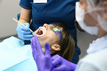 A dentist and assistant do a routine examination of the patient's mouth. The concept of health and beauty.