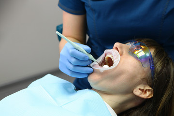 A dentist and assistant do a routine examination of the patient's mouth. The concept of health and beauty.