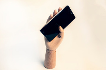 Wooden hand fastened a black mobile phone