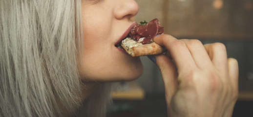 Beautiful young girl eats a slice of pizza in a cafe - Portrait of a beautiful girl eats.