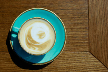 Cappuccino with frothy foam. Coffee in blue cup on wooden table. Top view with copyspace for your text. 