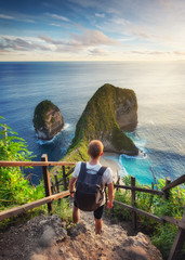 Traveler look at the ocean and rocks. Travel and active life concept. Adventure and travel on Bali,...