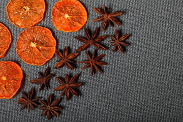 Tangerines are cut into slices and dried to decorate desserts. Nearby are the stars of anise. On a gray background.