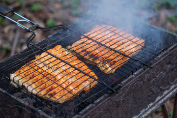 Two pieces of salmon fillet on the grill. Cooking process, close up