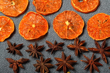 Tangerines are cut into slices and dried to decorate desserts. Nearby are the stars of anise. On a gray background.