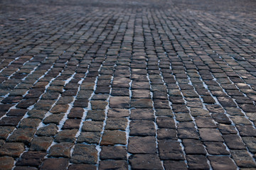 Stone pavement in perspective. Old street paved with stone blocks. Shallow depth of field. Vintage grunge texture.