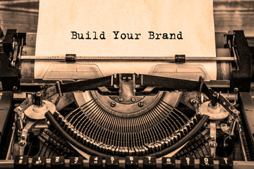 BUILD YOUR BRAND printed on a sheet of paper on a vintage typewriter. writer, journalist.
