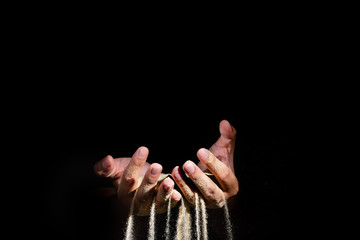 sand pouring though between the fingers on black background, failure concept
