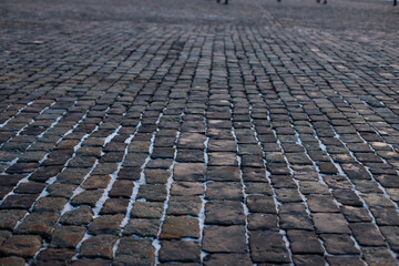 Fototapeta premium Stone pavement in perspective. Old street paved with stone blocks. Shallow depth of field. Vintage grunge texture.