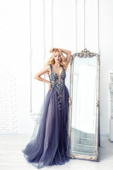 Luxurious young beautiful model blonde woman in a chic long dress in the interior