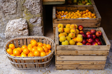 Ripe oranges, peaches, nectarines and plums in wooden boxes for sale