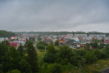 Fototapeta na wymiar View from top on small town with houses and trees in overcast day.