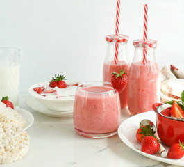 Strawberry smoothie or milkshake in a glass on white wooden background. Healthy food for breakfast and snack. copy space