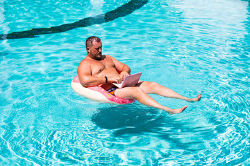 Dream job, a young man with a computer in the water on an inflatable circle,Man with a laptop on inflatable ring in the water