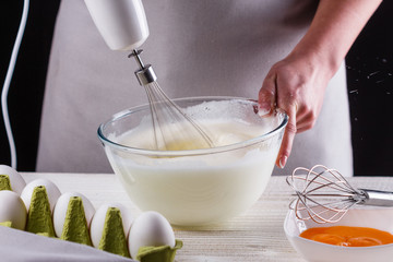 young woman in a gray aprons breaks the eggs