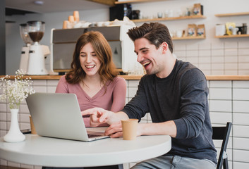 Two young people working with a laptop in a cafe and drinking coffee