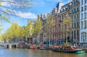Fototapeta na wymiar Amsterdam, Netherlands - April 09, 2019: Classic bicycles and historical houses in old Amsterdam. Typical street in Amsterdam with canal and colorful houses in the Dutch style on the Sunset.