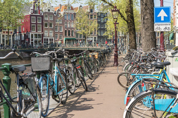 Amsterdam, Netherlands - April 09, 2019: Classic bicycles and historical houses in old Amsterdam. Typical street in Amsterdam with canal and colorful houses in the Dutch style on the Sunset.