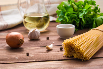  ingredients for cooking pasta raw spaghetti garlic onion parsley spices on wooden table close up