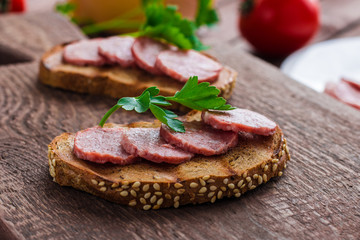 open sandwiches with sliced salami sausage parsley on rye bread on cutting board 