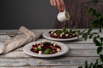 beetroot salad with goats cheese and walnuts, olive oil dressing pouring down onto a salad